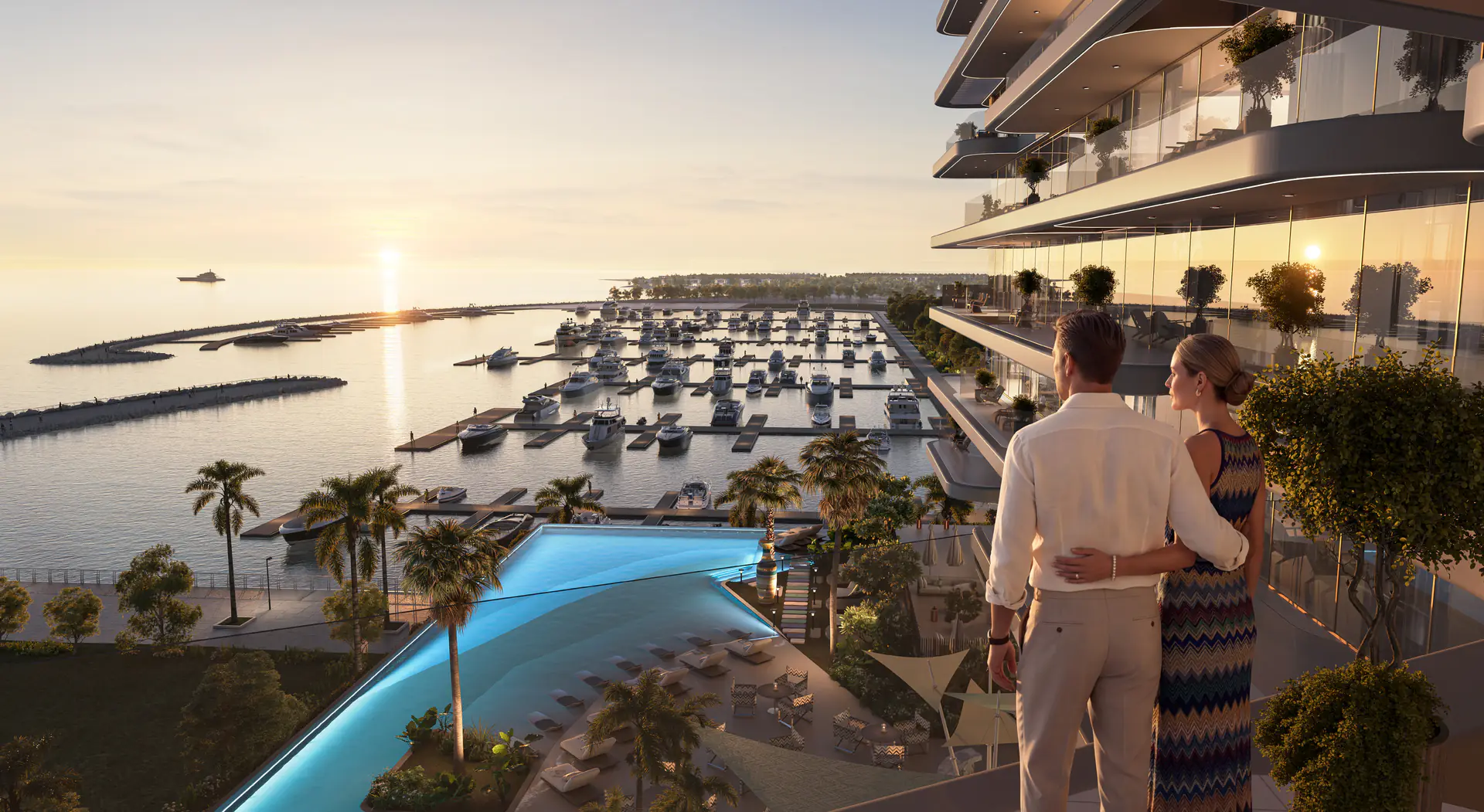 Couple on the seaside deck at The Bay Dubai Islands above the beach pool and Island A yacht marina at sunset